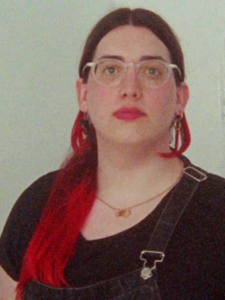 Paula Tomás Marques im Porträt. Eine Person mit langen roten Haaren und Brille.